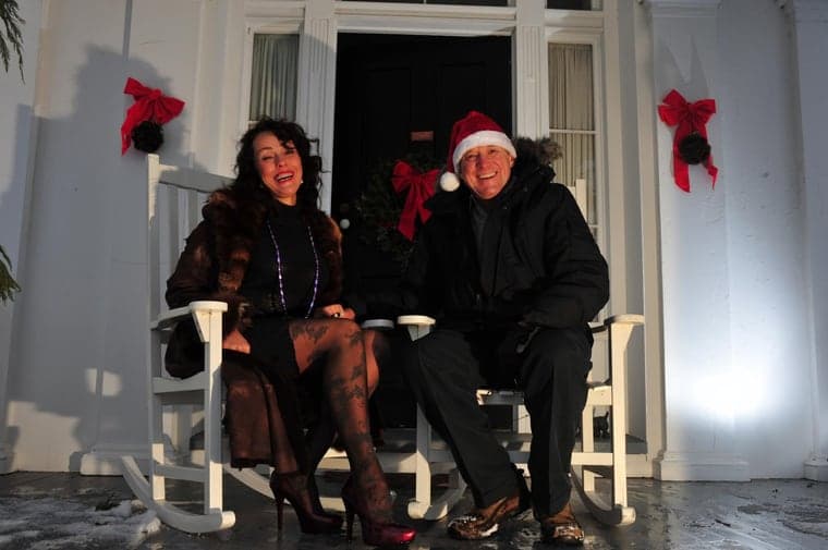The original photo: a couple in winter coats on rocking chairs on a porch decorated for Christmas, at night